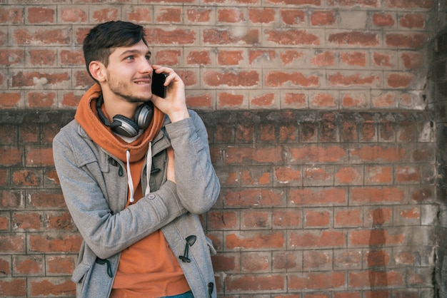 Junger Mann, der draußen am Telefon spricht.