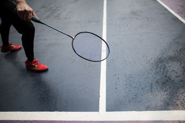 Junger Mann, der draußen Badminton spielt