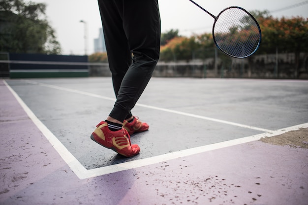 Junger Mann, der draußen Badminton spielt