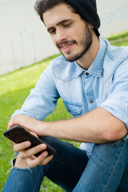 Junger Mann, der draußen sein Telefon verwendet