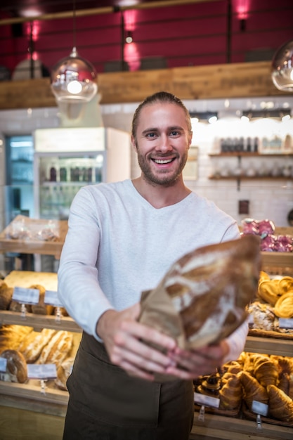 Junger Mann, der ein frisch gebackenes Brot hält