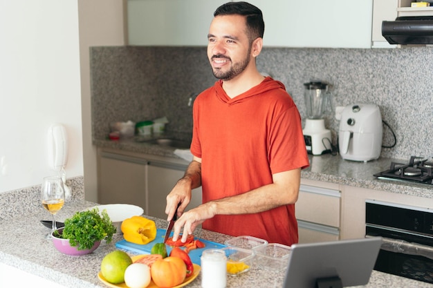 Junger Mann, der ein gesundes Mittagessen in der Küche kocht