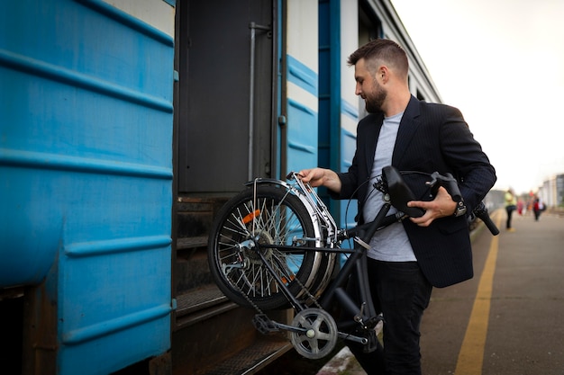 Junger Mann, der ein Klapprad benutzt, während er mit dem Zug fährt