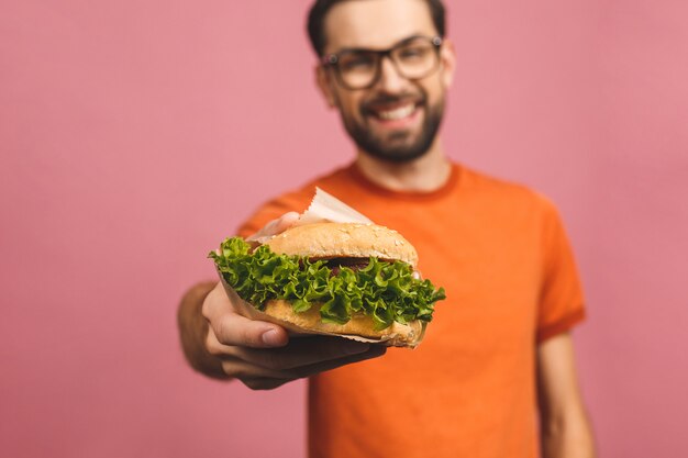 Junger Mann, der ein Stück Hamburger hält