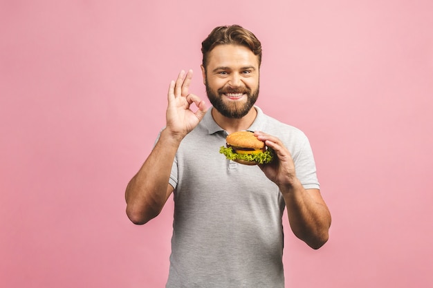 Junger Mann, der ein Stück Hamburger hält