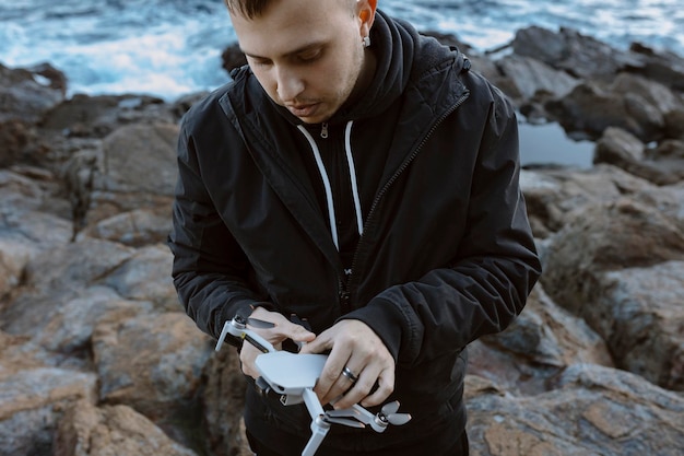 Junger Mann, der eine Drohne über dem Meer betreibt Foto in hoher Qualität