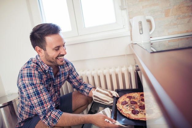 Junger Mann, der eine Pizza macht