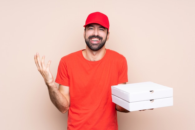 Junger Mann, der eine Pizza über dem lokalisierten Hintergrund lächelt viel hält