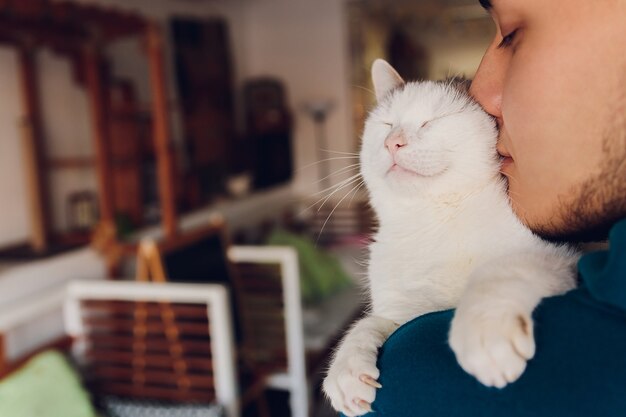 Junger Mann, der eine weiße Katze Nahaufnahme hält.