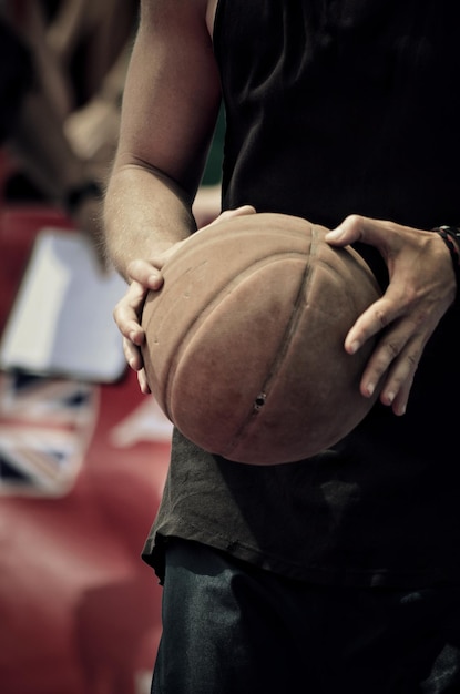 Junger Mann, der einen Basketballball hält.