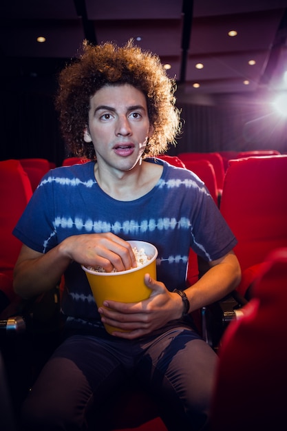 Junger Mann, der einen Film aufpasst und Popcorn isst