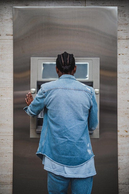 Junger Mann, der einen Geldautomaten benutzt, um Geld abzuheben Er reist ins Ausland und braucht etwas Bargeld