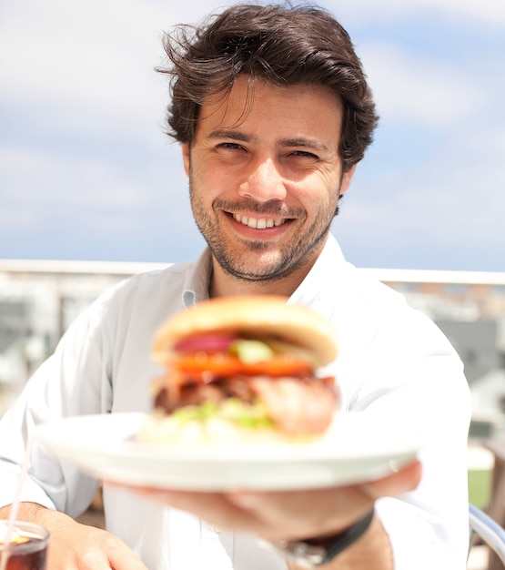 Junger Mann, der einen Hamburger isst