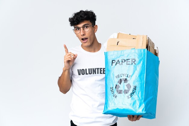 Junger Mann, der einen Recyclingbeutel voll Papier hält, der beabsichtigt, die Lösung zu realisieren, während er einen Finger anhebt