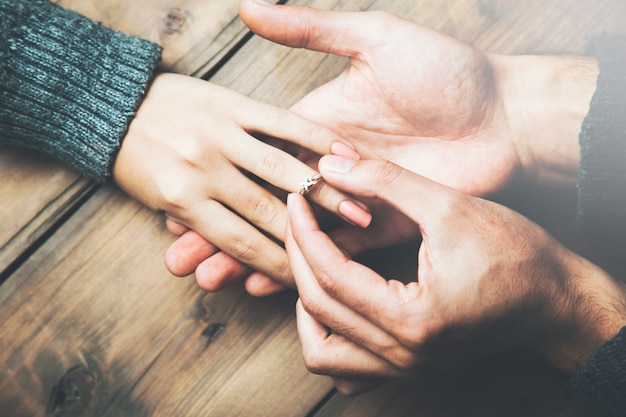 Junger Mann, der einen Ring auf die Hand der Frau legt