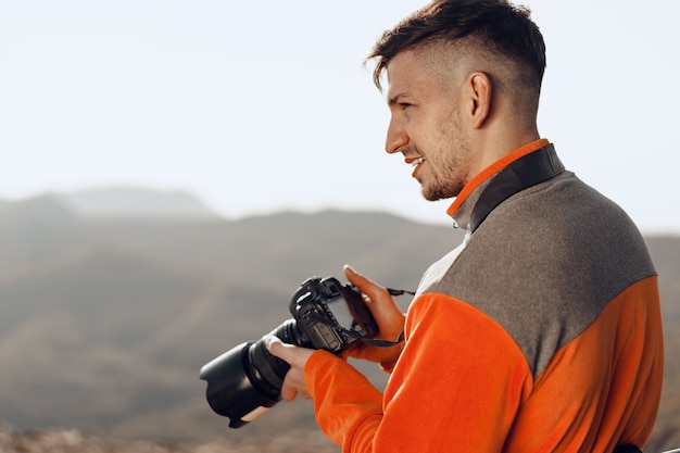 Junger Mann, der Fotos von Bergen mit professioneller Kamera macht