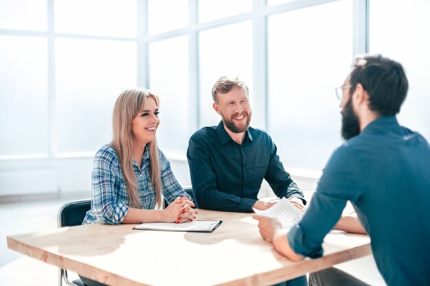 Junger Mann, der Fragen von Interviewern im Büro beantwortet. Konzept der Zusammenarbeit