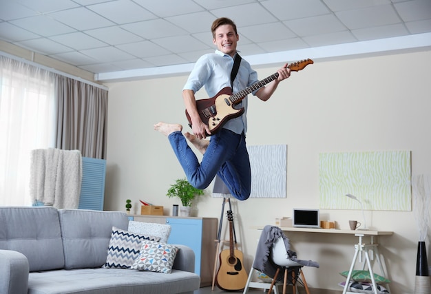 Junger Mann, der Gitarre in einem Raum spielt