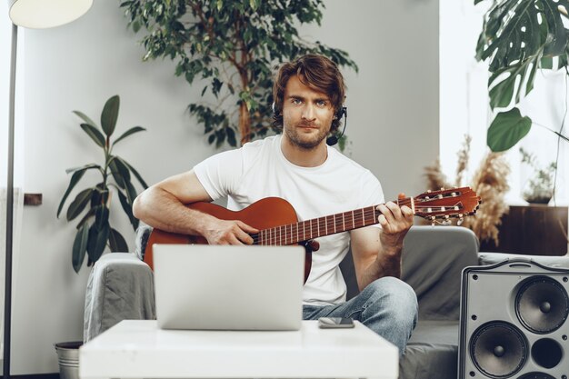 Junger Mann, der Gitarrentutorial auf seinem Laptop beobachtet