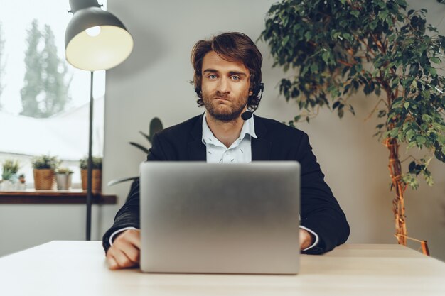 Junger Mann, der Headset trägt, der einen Videoanruf durch Laptop tut