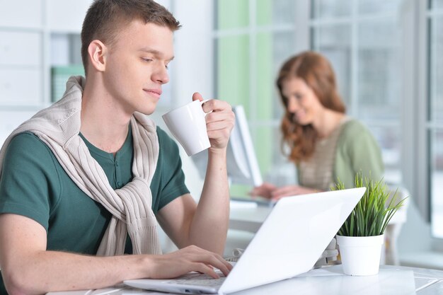 Junger Mann, der im Büro mit einem Laptop arbeitet