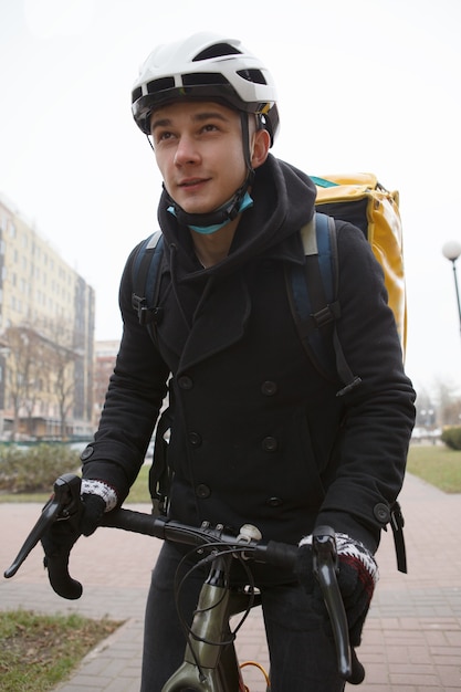 Junger Mann, der im Lieferservice arbeitet, Fahrrad in der Stadt reitend, Thermorucksack tragend