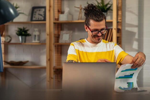 Junger Mann, der im modernen Büro arbeitet und Technologie nutzt, um seine Arbeit zu erledigen