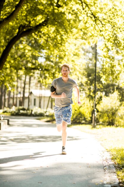 Junger Mann, der in den Herbstpark läuft