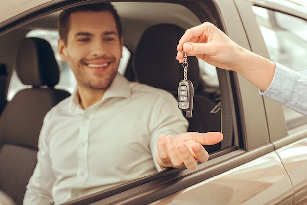 Junger Mann, der in der Nähe des Autos steht und den Schlüsselverleih bekommt