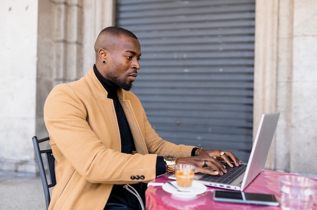 Junger Mann, der in einem Café sitzt und Laptop verwendet.