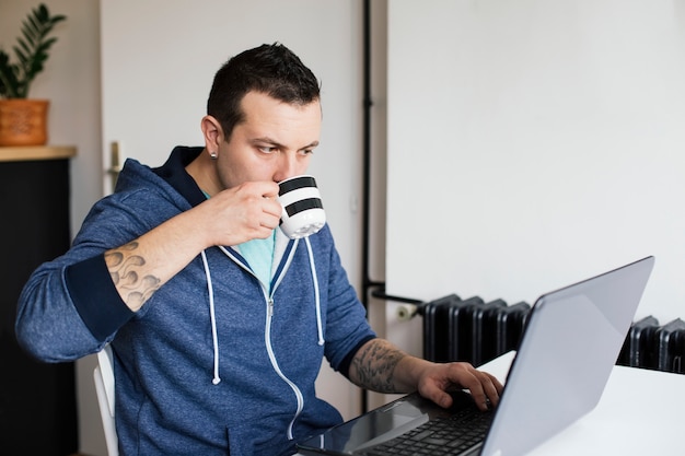 Junger Mann, der Kaffee trinkt und arbeitet