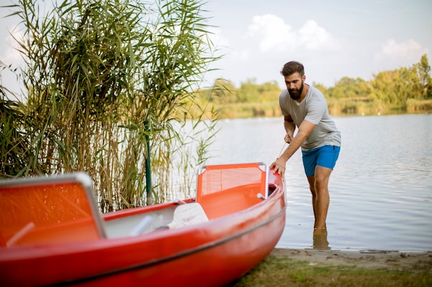 Junger Mann, der Kanu in ruhigen See zieht