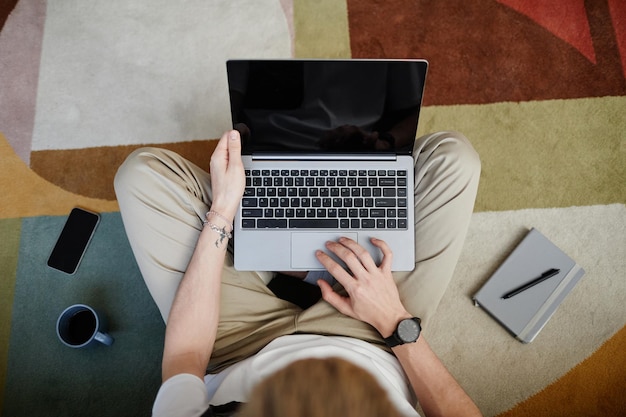 Junger Mann, der Laptop-Draufsicht verwendet