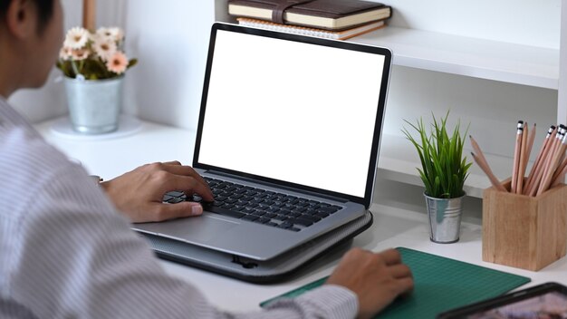 Junger Mann, der Laptop-Kontaktgeschäftssuchinformationen auf Schreibtisch im Büro verwendet