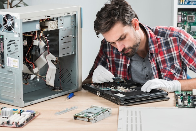 Foto junger mann, der laptop ram auf hölzernem schreibtisch betrachtet