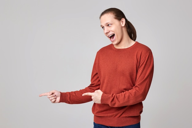 Junger Mann, der mit dem Finger auf den leeren Raum zeigt