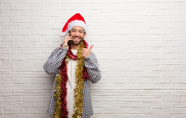Junger Mann, der mit den Geschenken feiern Weihnachten oben lächelt und anhebt