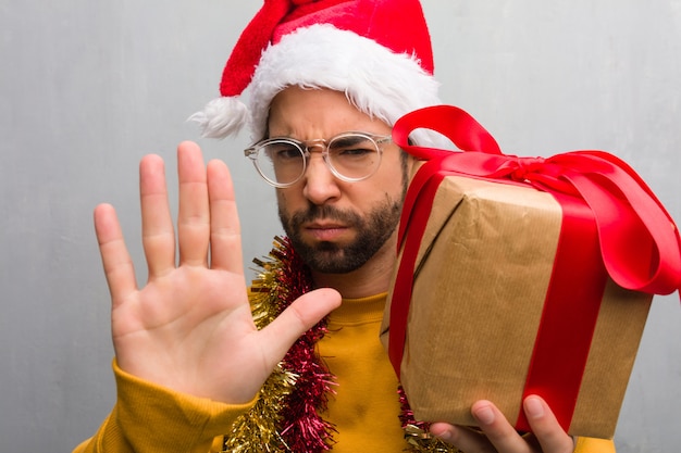 Junger Mann, der mit den Geschenken feiert Weihnachten feiert Hand in Front setzen sitzt