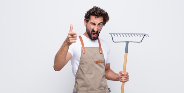 Junger Mann, der mit einem wütenden aggressiven Ausdruck auf Kamera zeigt, der wie ein wütender, verrückter Chef aussieht