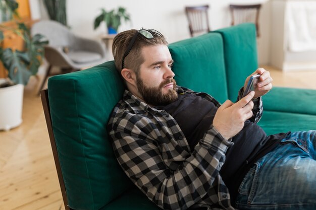 Junger Mann, der mit Smartphone auf Social-Networking-Site surft. Technologien und Internet-Konzept.