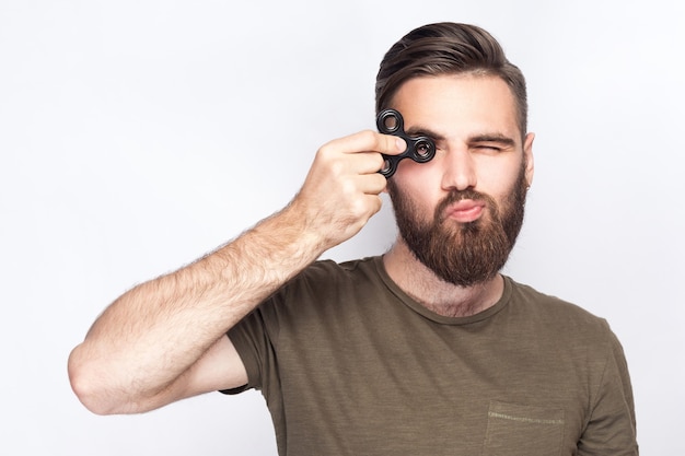 Junger Mann, der mit Zappelspinner hält und spielt. Studioaufnahme auf weißem Hintergrund. .