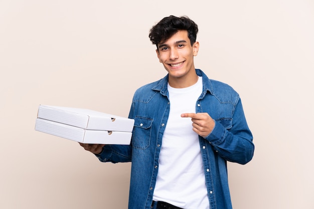 junger Mann, der Pizzakästen über lokalisierter Wand hält