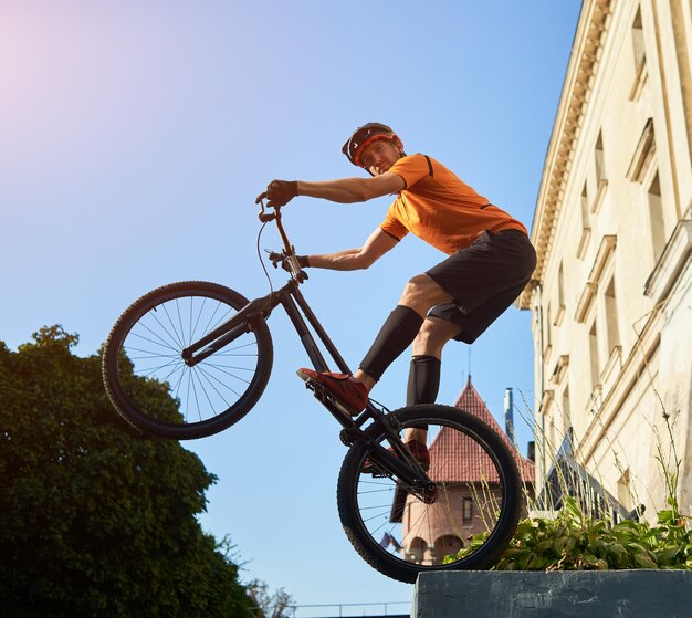 Junger Mann, der radikale Mountainbike-Sprünge in der Altstadt durchführt