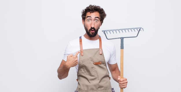 Junger Mann, der schockiert und überrascht mit weit geöffnetem Mund aussieht und auf sich selbst zeigt