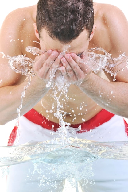 Junger Mann, der sein Gesicht mit sauberem Wasser wäscht und Hygiene- und Schönheitskonzept des Mannes repräsentiert