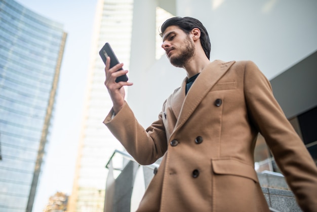 Junger Mann, der sein Handy im Freien benutzt