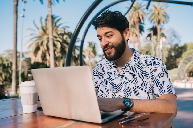 Junger Mann, der seinen Laptop in einem Café benutzt