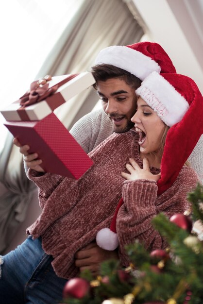 Junger Mann, der seiner Freundin Weihnachtsgeschenk gibt