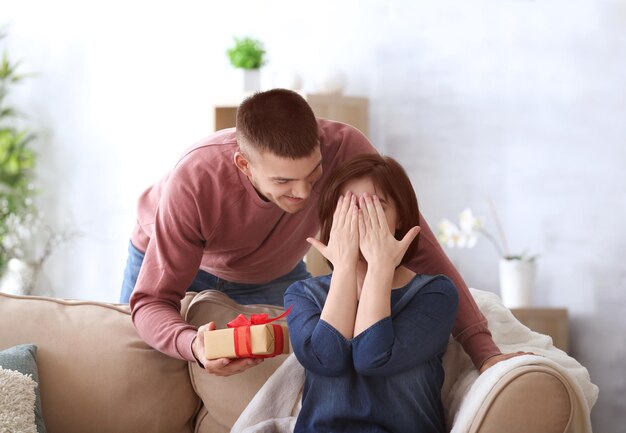 Junger Mann, der seiner Freundin zu Hause ein Geschenk gibt