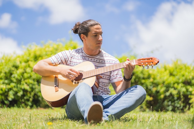 junger Mann, der spanische Gitarre auf dem Feld spielt